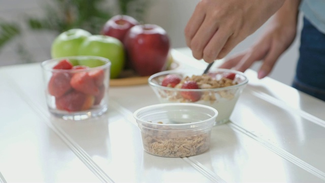女士亲手准备健康的早餐食品，酸奶配麦片和水果，健康的生活理念视频下载