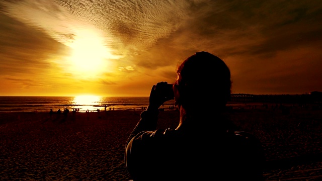 女人在海滩上拍摄日落的慢动作250帧/秒视频素材