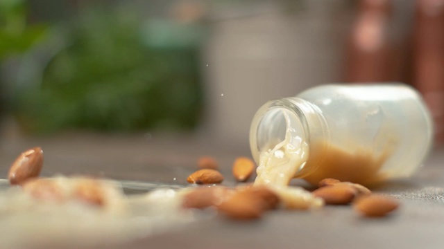慢镜头，宏镜头:新鲜的杏仁牛奶洒在了生的有机杏仁上。视频素材