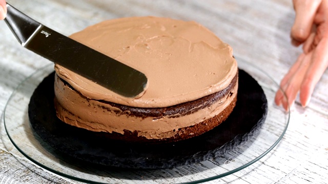 糕点的特写覆盖着奶油巧克力海绵蛋糕。巧克力蛋糕。奶油装在糕点袋里。假日吃巧克力蛋糕。视频下载