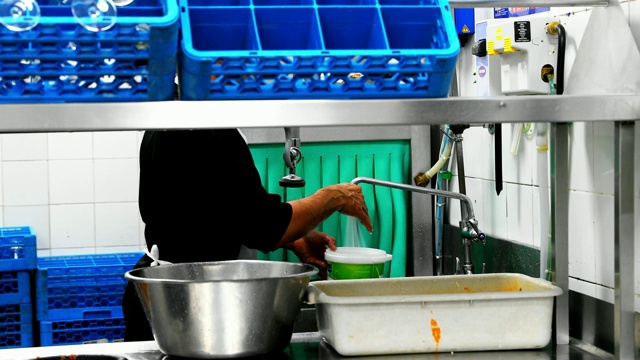 男人在商业厨房里洗餐具视频下载