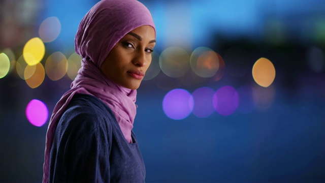身着头巾的黑人妇女在散景灯光下站在城市中视频下载