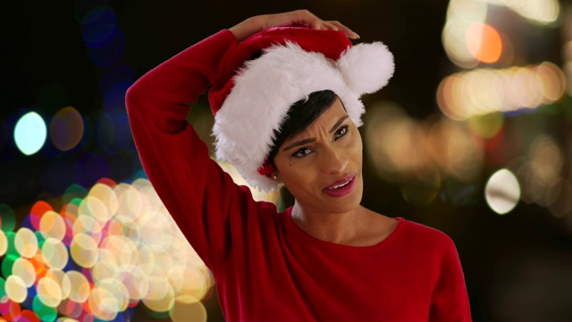 活泼的年轻女子在户外与散焦灯设置圣诞帽造型视频下载