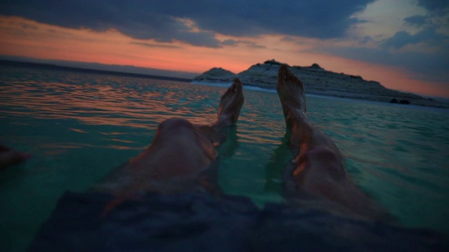 一个度假的家伙在死海里漂浮着夕阳的余晖。视频下载