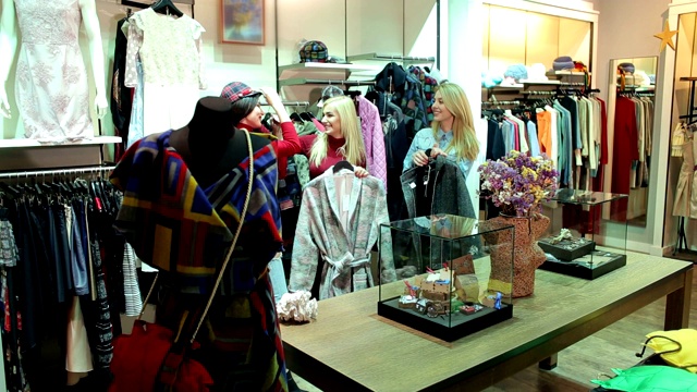三个有趣的年轻女孩在店里挑选衣服。视频下载