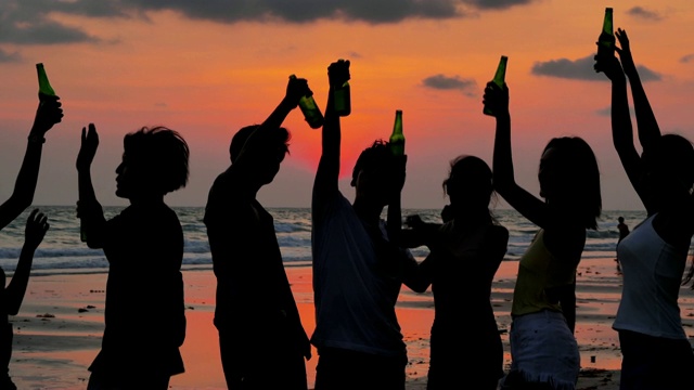一群朋友在海滩上玩和喝酒的剪影。假期——iStock视频素材