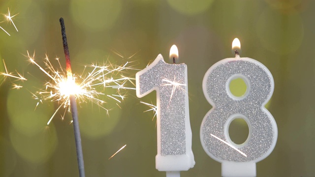 18号生日庆祝蜡烛在明亮的灯光和金色的散景背景下视频下载