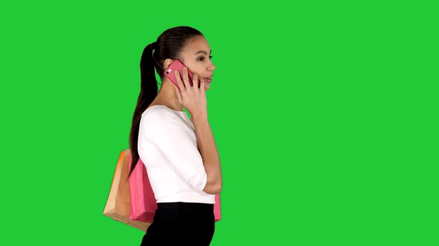 兴奋的女人用绿色屏幕上的购物袋打电话，色度键视频素材