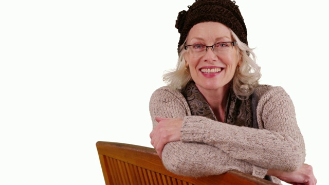 戴眼镜的老妇人坐在工作室的长椅上对着镜头微笑视频素材