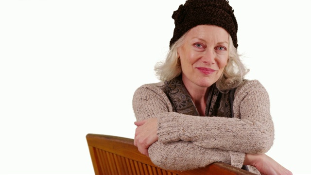 年长的女人坐在长椅上，对着镜头微笑视频素材