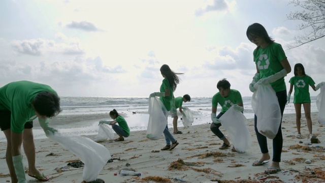 一群快乐的志愿者用垃圾袋清理海滩上的区域。志愿、慈善、清洁、人与生态的观念视频素材