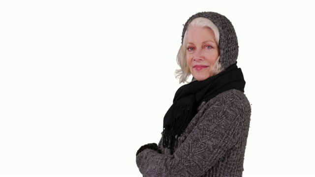 年长的妇女在温暖的衣服看着相机与和善的微笑在工作室视频素材