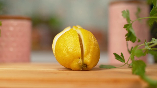 慢镜头，微距:切成四等分的新鲜柠檬落在厨房的木制桌子上。视频素材