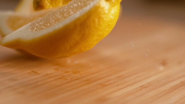 微距:芳香的亮黄色柠檬片落在木质切菜板上。视频素材