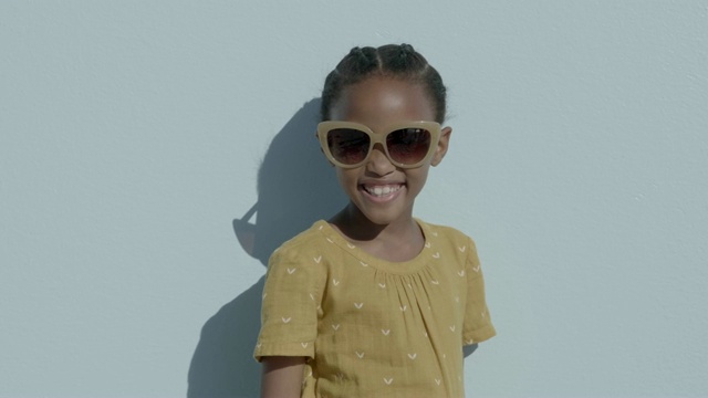 蓝色背景下戴着太阳镜的快乐女孩视频素材
