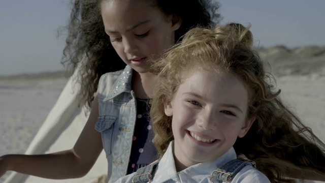 女孩在海滩上玩快乐朋友的头发视频素材