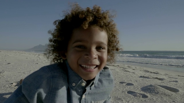 微笑的男孩和女孩在海滩上对着天空奔跑视频素材