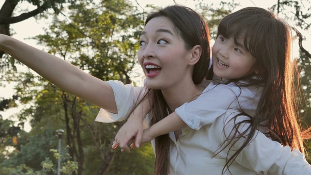 生活方式的母亲和女儿在幸福的在野外在日落的光。家人在做节日活动。亚洲家庭在花园里玩耍。幸福的家庭的概念。放松的育儿视频素材
