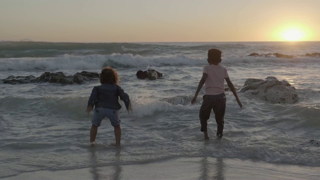 快乐的男孩在日落的海浪中享受视频素材