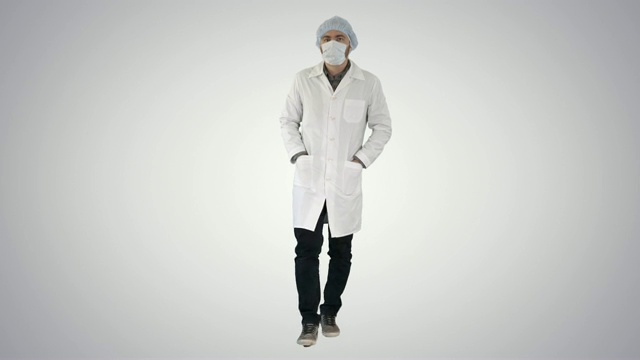 走路的年轻男医生戴着外科口罩在梯度背景视频素材