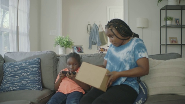 非洲裔美国妇女走到门口接受包裹，并把盒子给她的儿子。视频下载