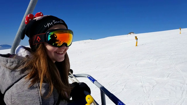 在一个阳光明媚的日子里，兴奋的小女孩乘坐滑雪缆车视频素材