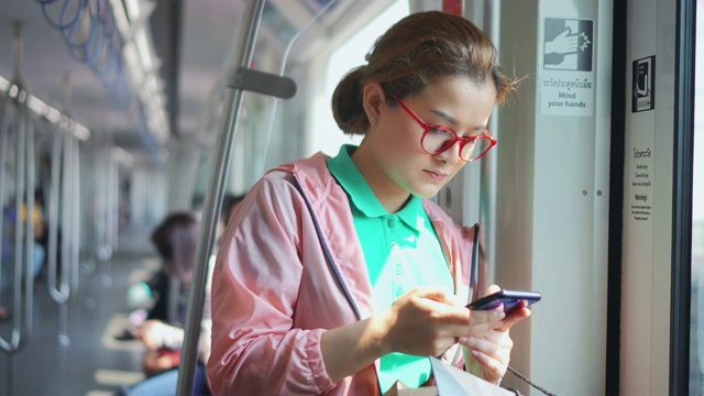 年轻女子在乘坐地铁时使用智能手机视频素材