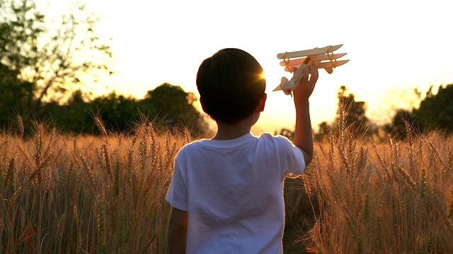 可爱的亚洲小孩在日落时分的稻田里玩玩具飞机。视频素材