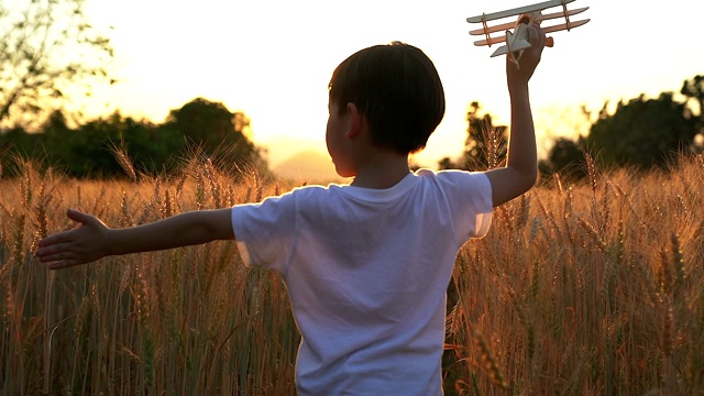 可爱的亚洲小孩在日落时分的稻田里玩玩具飞机。视频素材