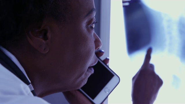中年黑人医学博士用手机与病人谈论x光视频素材
