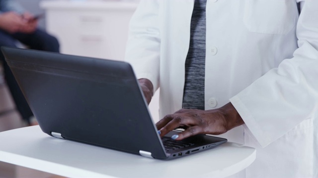笔记本电脑和高级非洲医生打字的特写视频下载