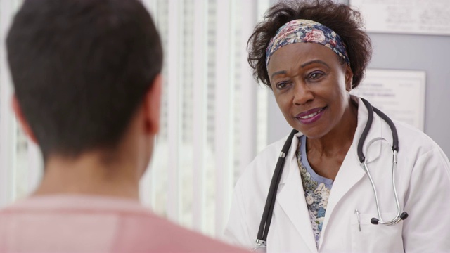 积极的女非洲医生与男性病人在医疗办公室交谈视频素材