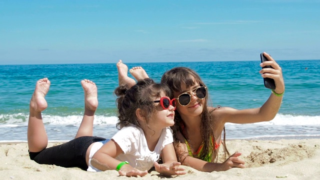 孩子们在海滩上拍照。姐妹们躺在沙滩上。视频下载