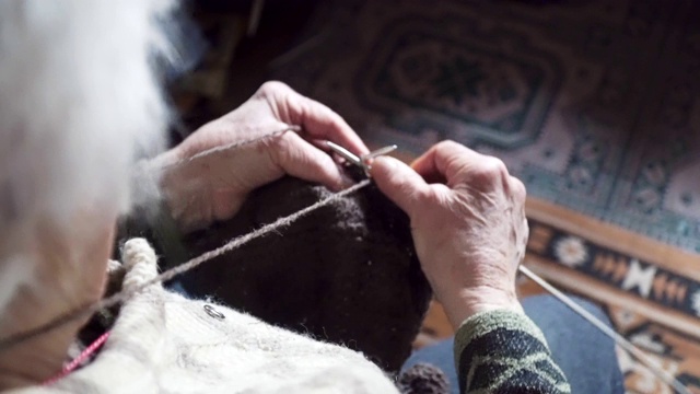 观点。一位老人织着精致而美观的毛衣，近处是一位老奶奶满是皱纹的双手正在织一件新的冬季毛衣，活跃的退休老人。视频下载