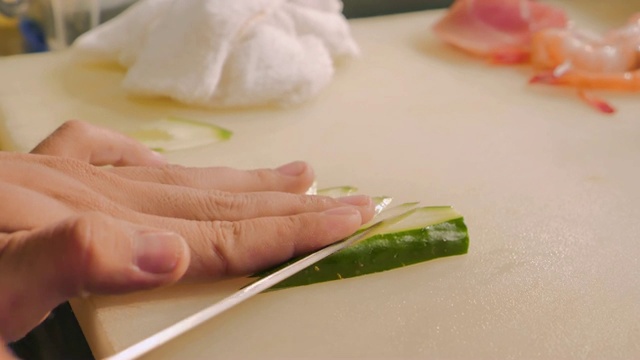 厨师手准备日本食物的特写。厨师在切菜板上准备新鲜的黄瓜，日本厨师在餐厅做寿司。视频素材