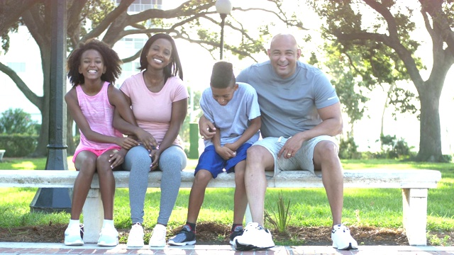 跨种族家庭跑过来，一起坐在公园的长椅上视频素材