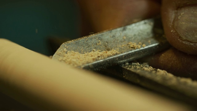 一个人在用凿子雕刻车床上的木头的旋转销子视频素材
