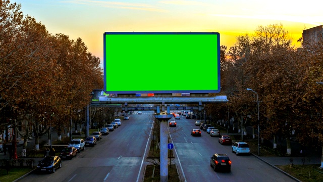 一个广告牌与绿色色度键在背景快速移动的汽车在日落。镜头移开了。视频下载