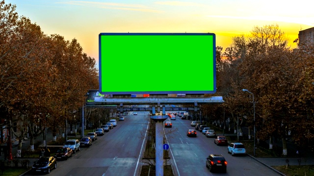 一个广告牌与绿色色度键在背景快速移动的汽车在日落。时间流逝的视频。摄影机过来了。视频下载