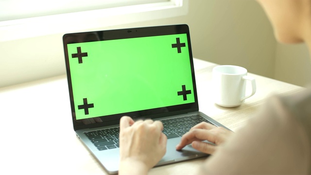 一位女士正在看她的绿屏笔记本电脑视频素材