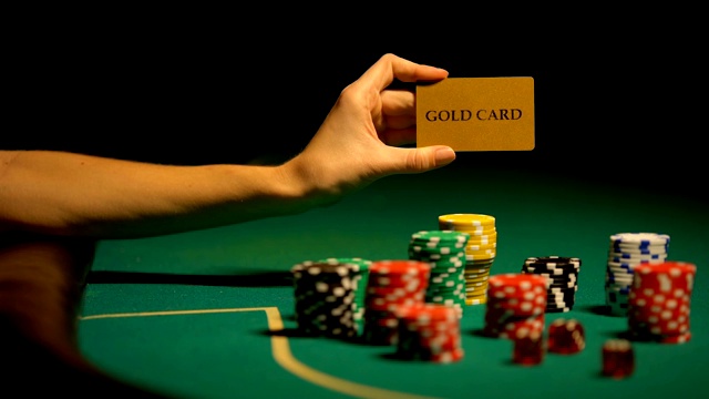 手里拿着金卡，桌上放着筹码，为vip客户提供非法赌场视频下载
