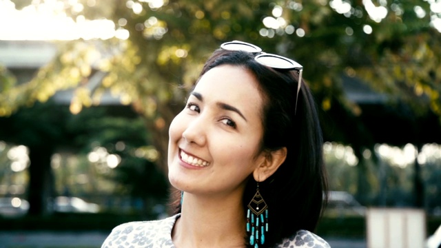 年轻美丽的亚洲女人的肖像快乐和微笑看起来友好的户外相机。缓慢的运动。视频素材