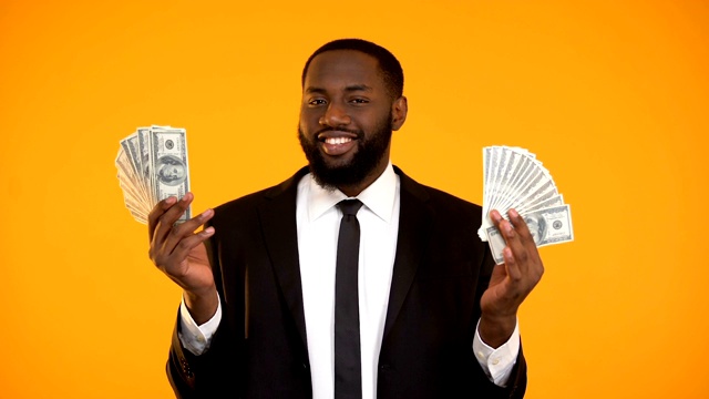 性感的非裔美国男性在西装玩美元钞票和使吻视频素材