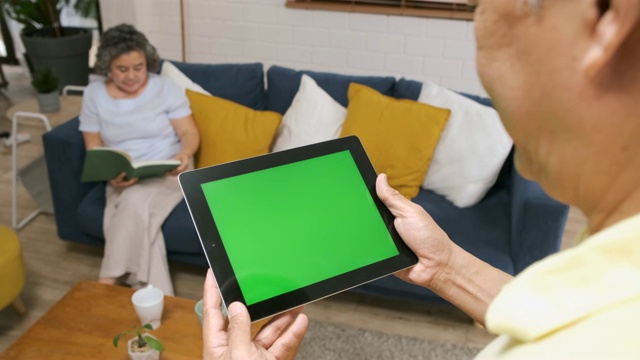 老人用绿屏平板电脑app来控制家里客厅里的空调和妻子。智能家居自动化控制概念。视频素材