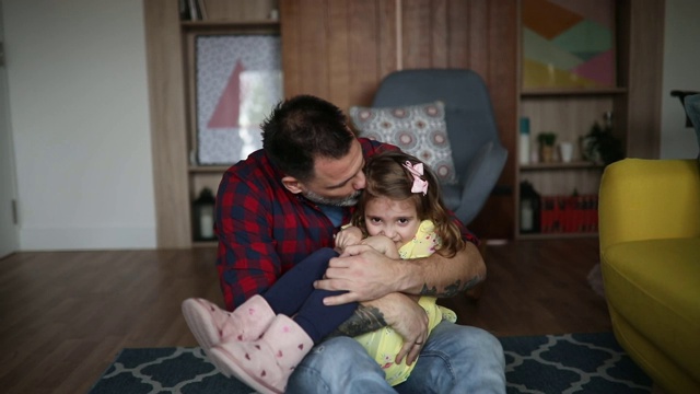 父亲和女儿拥抱在一起，坐在地板上聊天视频素材