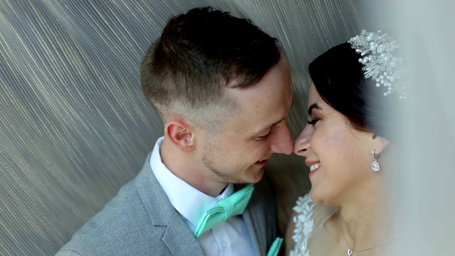 幸福恩爱的新婚夫妇站在窗边拥抱并轻轻亲吻。视频下载
