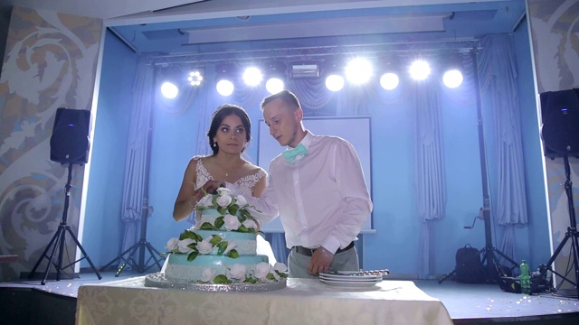 这对新婚夫妇切了一个漂亮的白色花结婚蛋糕。视频素材