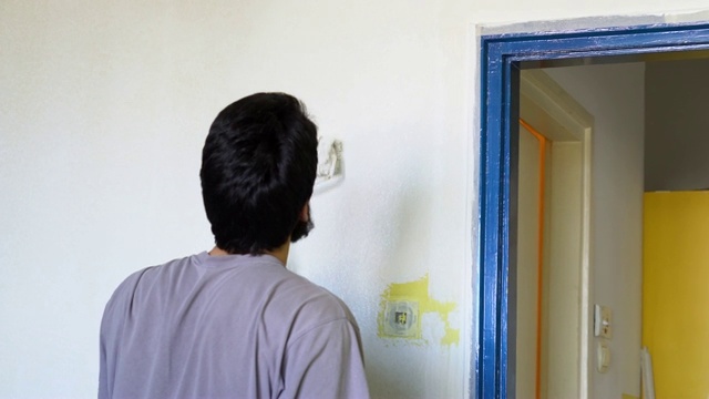 一个年轻人正在粉刷他公寓的内墙视频素材