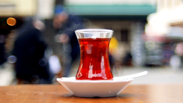 路边茶馆的桌子上放着土耳其茶，背景是一些模糊的人视频素材