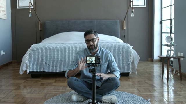 男人在家里的卧室里边拍视频边说话视频素材